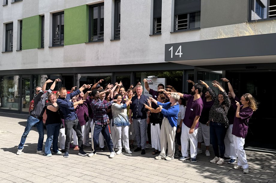 Mitarbeitende des AWO-Seniorenzentrums Am Zollhof stehen vor dem Eingangsbereich und verabschieden eine Person.